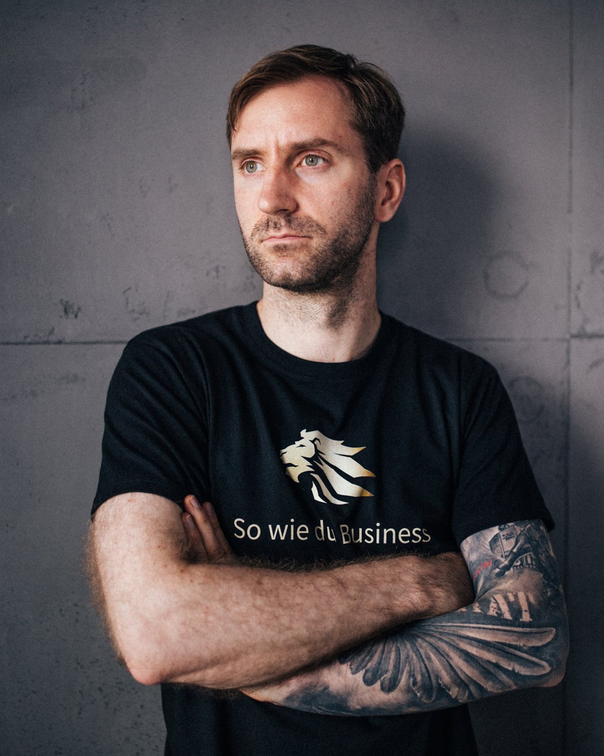 Dennis Herrmann mit verschränkten Armen vor einer Betonwand